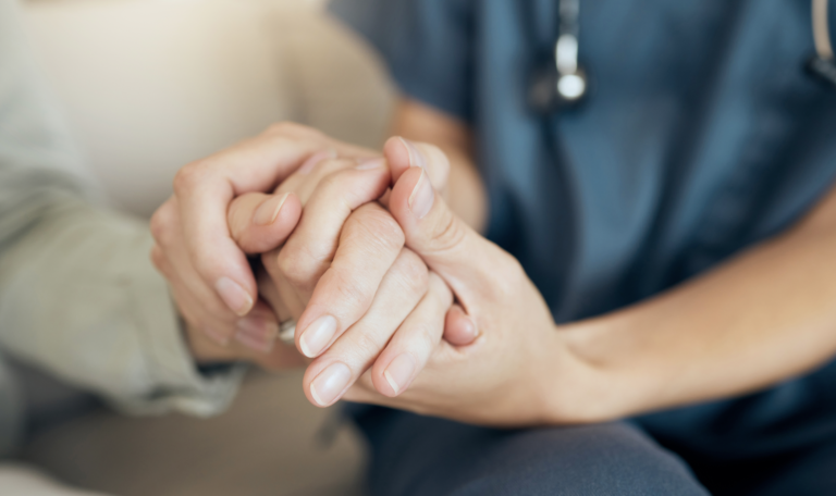Private duty nurse holding patients hand for post-op visit at home for in-home care recovery.